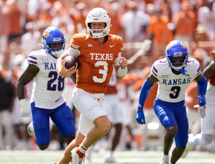 Texas Longhorns quarterback Quinn Ewers runs past Kansas Jayhawks linebacker, left, and cornerback Mello Dotson for a touchdown in the first quarter at Royal-Memorial Stadium.